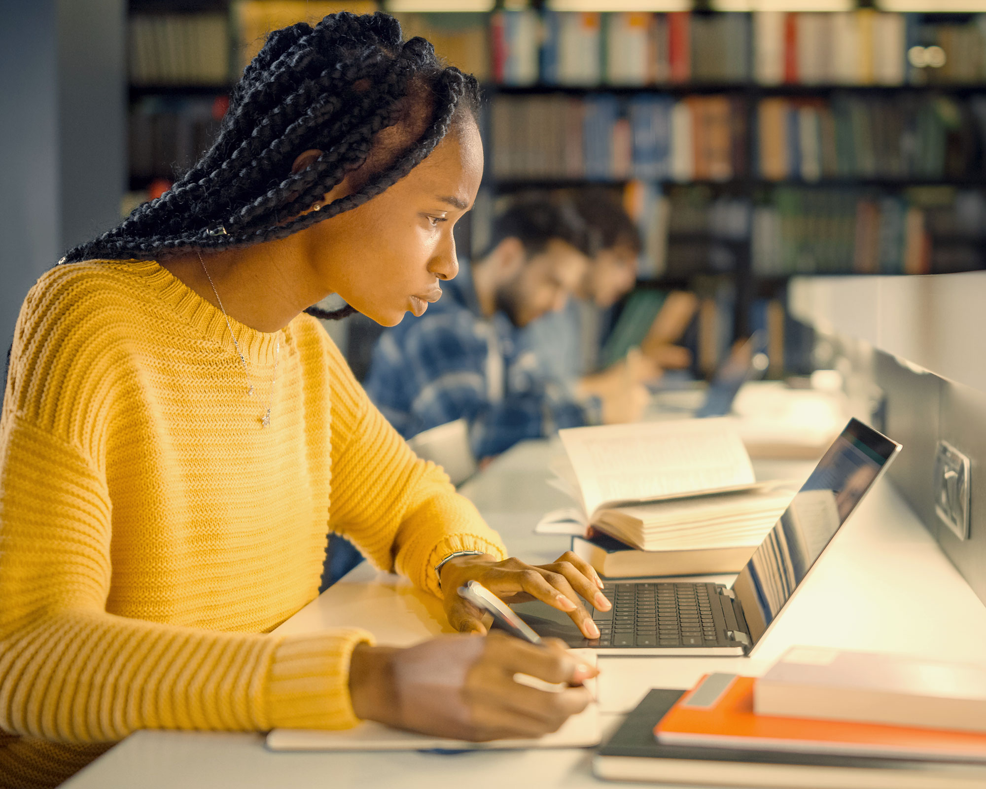 Student writing an essay in a library.