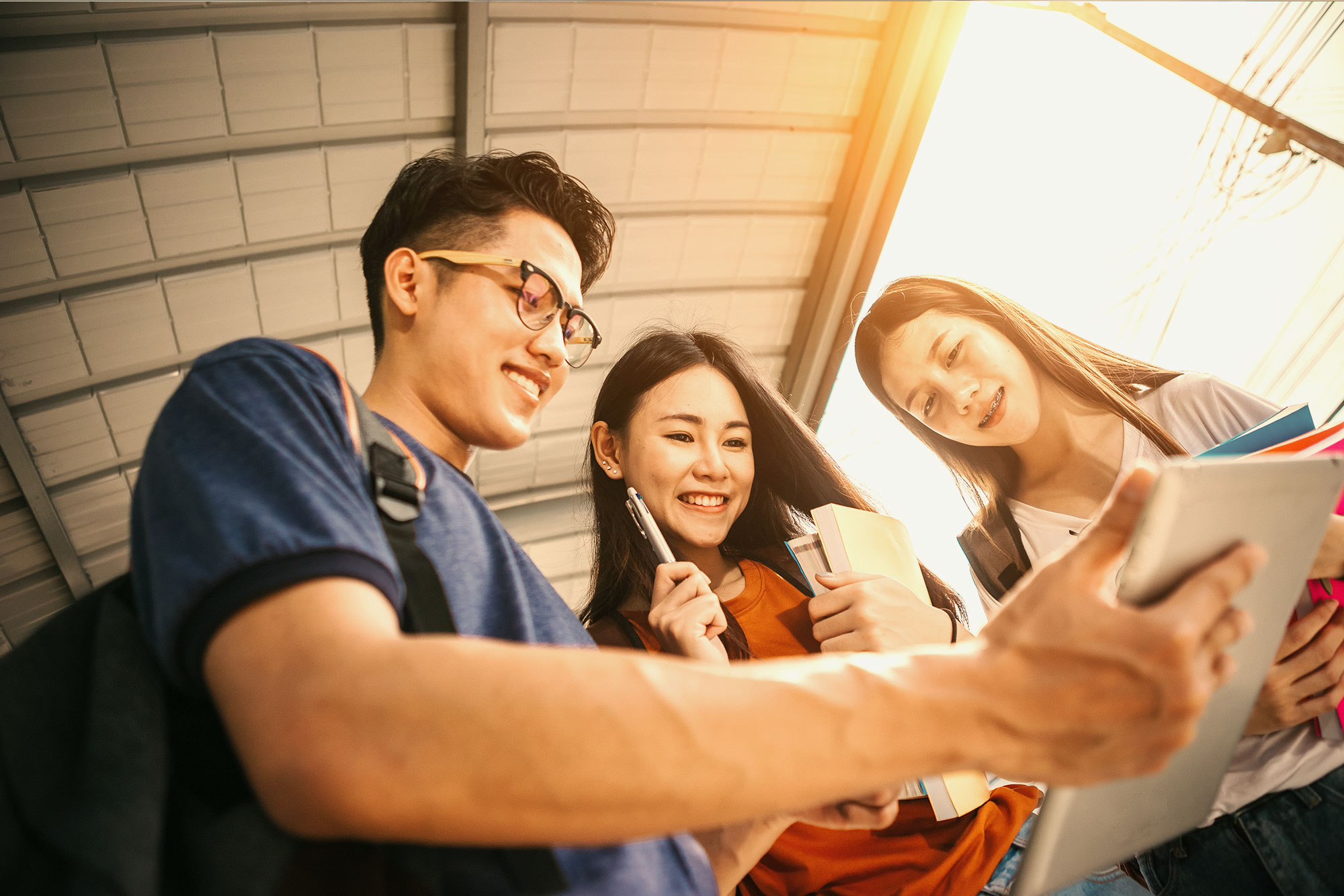 Three students look at a notebook together.