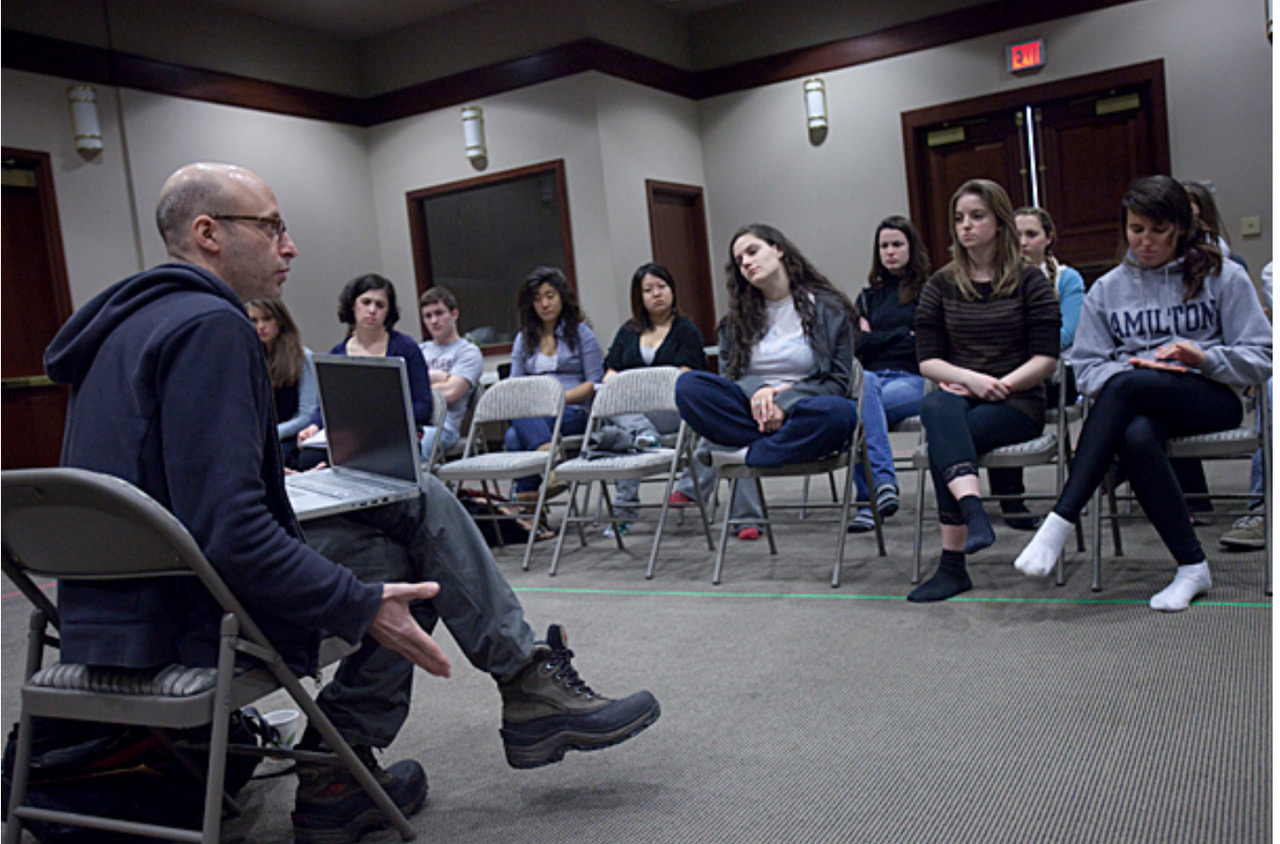 An instructor sits in front of a class of Harvard Summer School students.